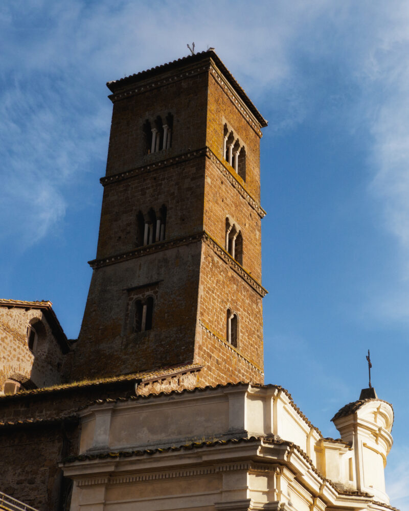 Campanile medievale in mattoni visto dal basso contro il cielo azzurro