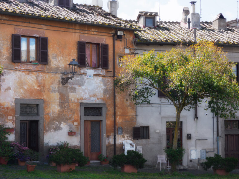 Strada principale di un borgo in discesa verso una porta medievale