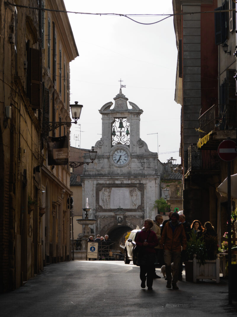 Strada storica con torre dell'orologio barocca in fondo alla via