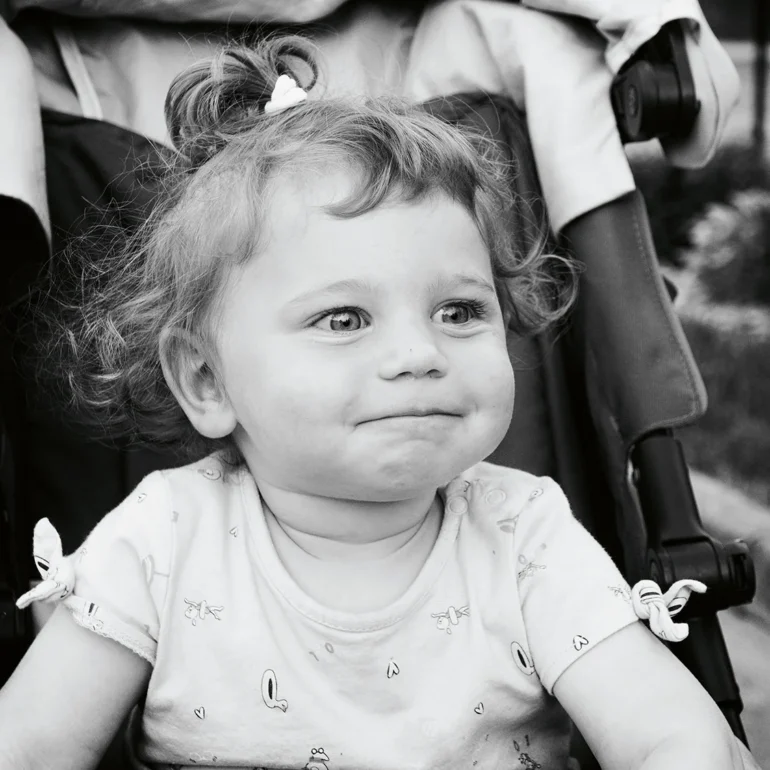 Bambina su passeggino che fa fatica a trattenere la risata