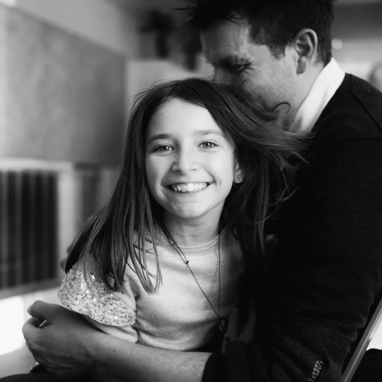 Bambina tenuta in braccio con sorriso bellissimo che guarda verso fotografo