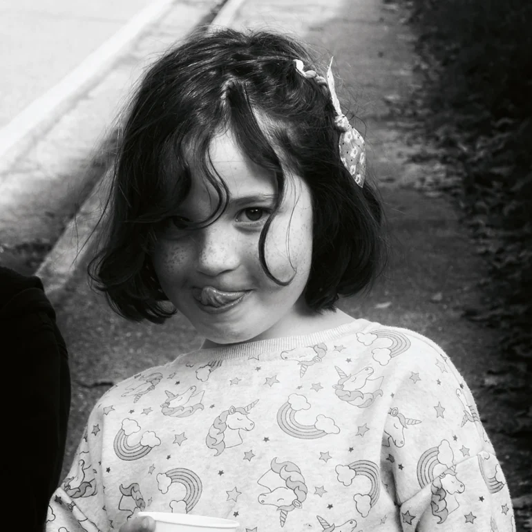 Bambina con in mano gelato, sguardo furbo che tira fuori la lingua