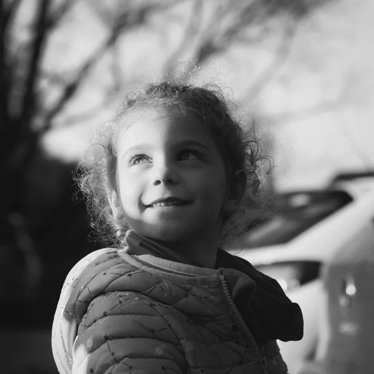 Bambina con sorriso e sgardo delicato con luce che illumina la faccia a metà