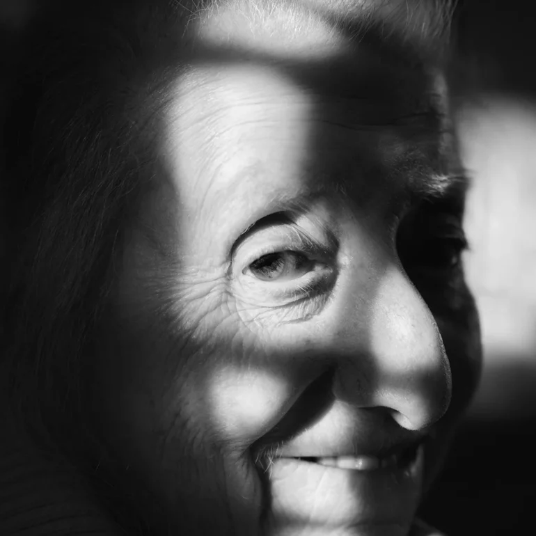 Donna anziana son sorriso accennato. Ritratto con gioco di luci.