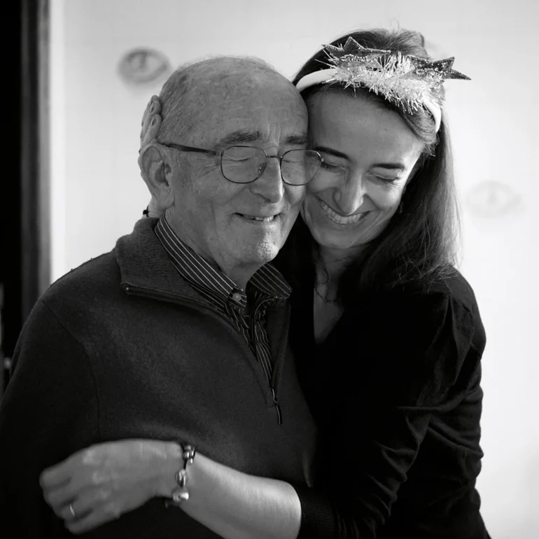 Padre e figlia che si abbracciano ad una festa sorridendo entrambi con occhi chiusi. Ritratto mezzo busto in bianco e nero