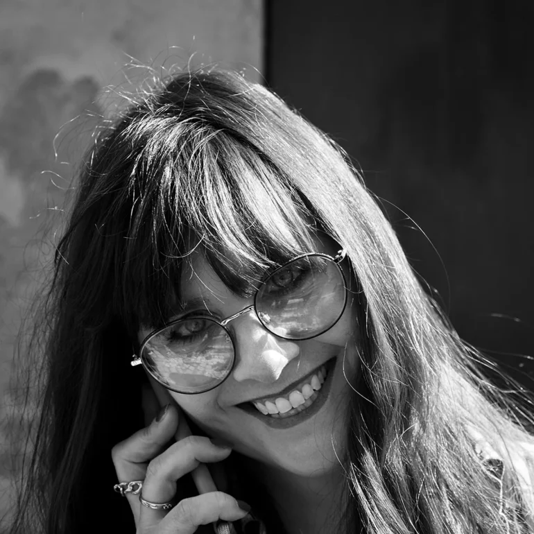 Primo piano in bianco e nero di una ragazza che sorride mentre parla al telefono