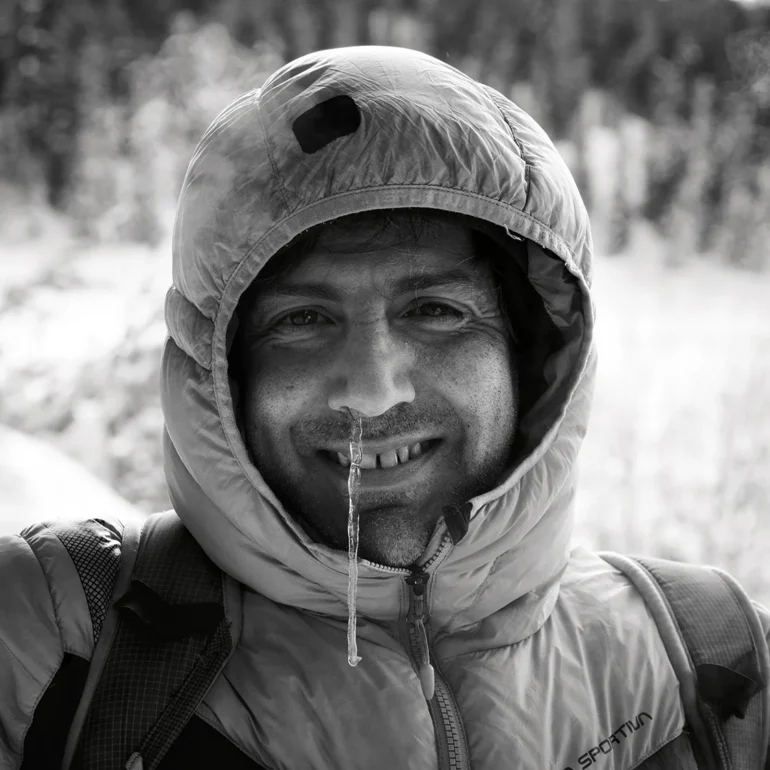 uomo vestito da alta montagna che scherzosamente si è messo una candela di ghiaccio nel naso